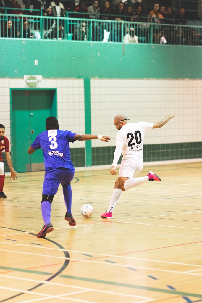 Action-packed indoor futsal game with two intense players competing for ball control on the court.