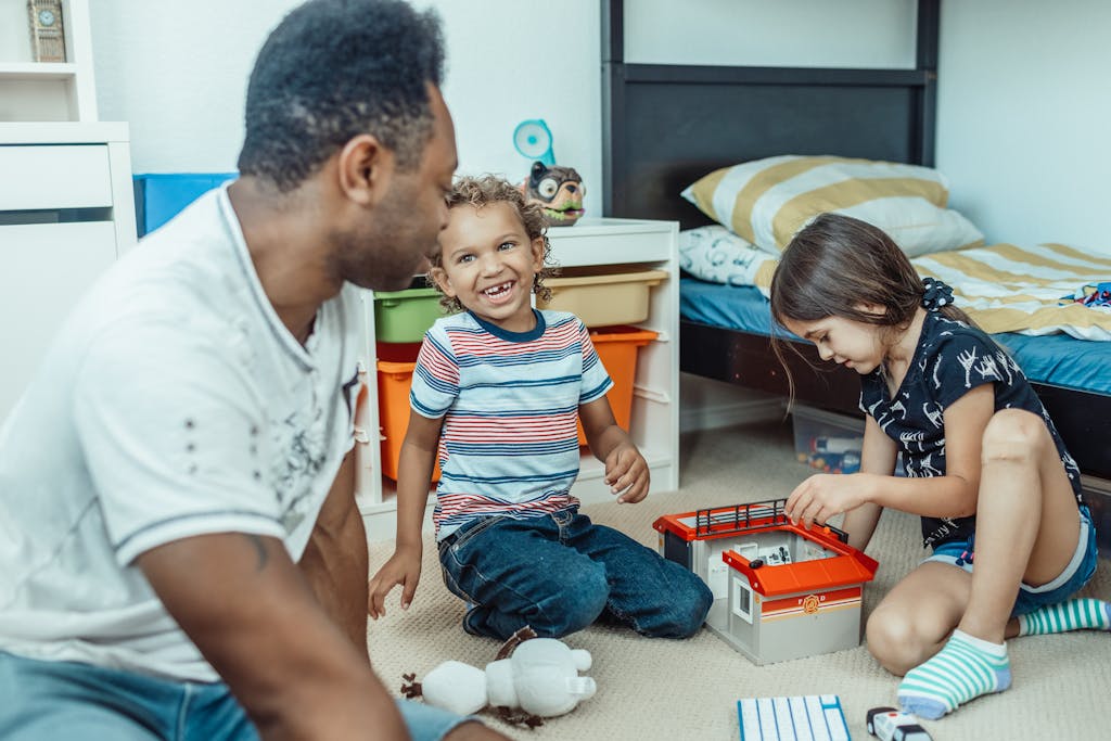 Father and children enjoy playtime together in a cozy bedroom environment.