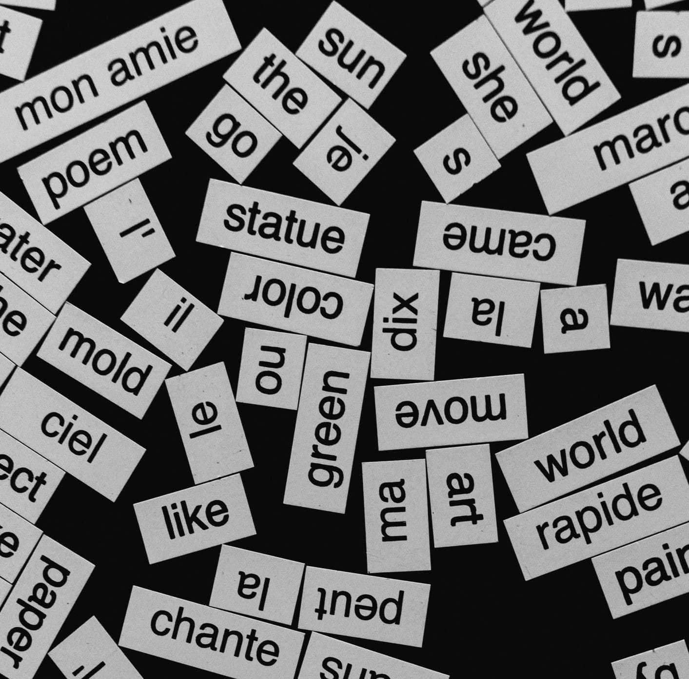 A close-up of various word cutouts on a black background, featuring different languages.