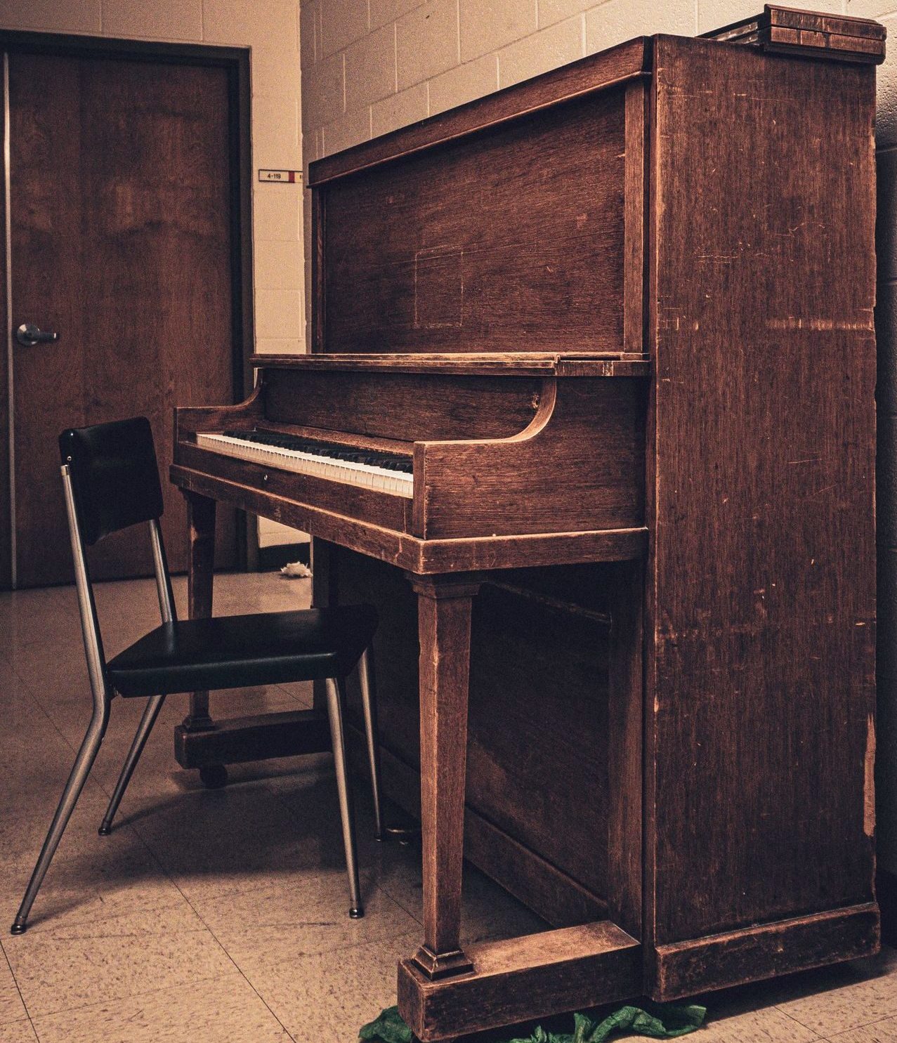A retro-styled wooden piano in an empty room with vintage decor.