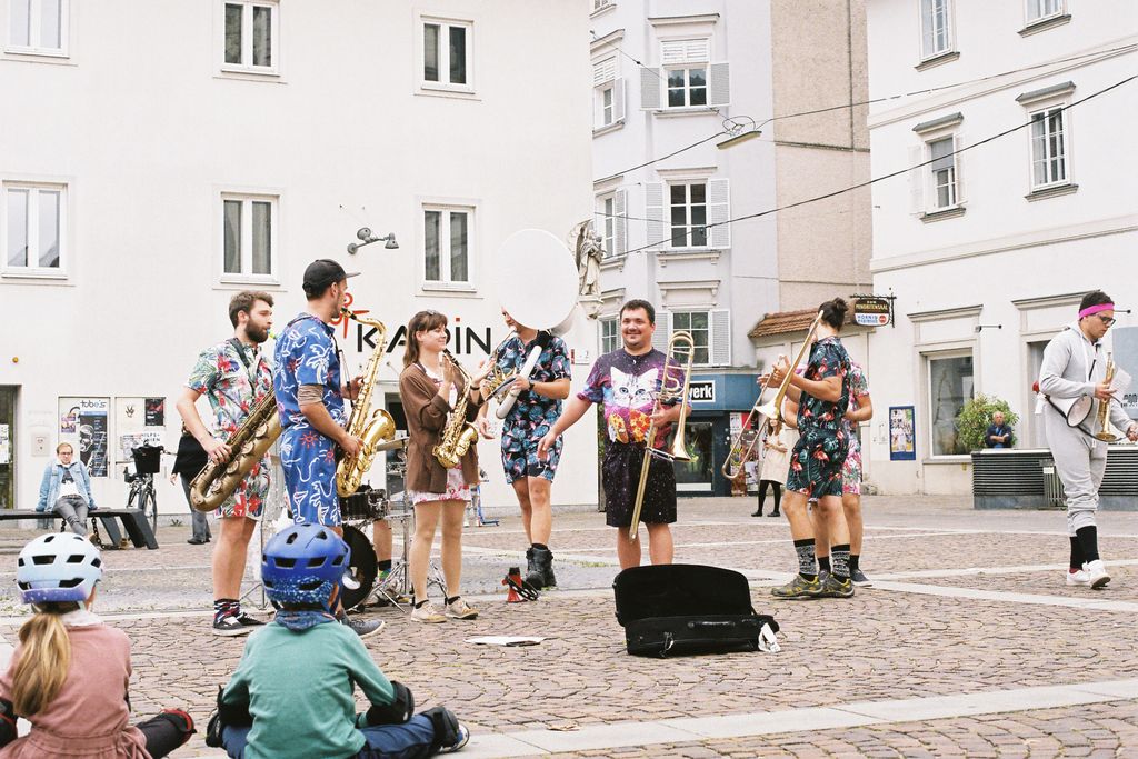 Vibrant street band in Hawaiian shirts playing instruments outdoors, entertaining a diverse crowd.